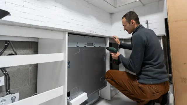 Persona instalando el lavavajillas panelable en la cocina.