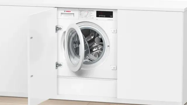 Secadora con bomba de calor, instalada en un amplio cuarto de lavado, junto a una estantería con ropa limpia y un cesto de ropa para lavar