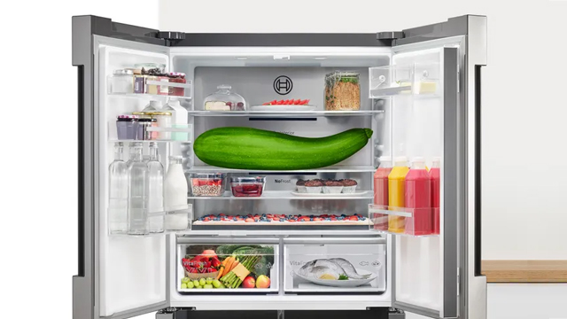 Refrigerador con las dos puertas abiertas. En su interior destacan una tarta de gran longitud y un calabacín gigante