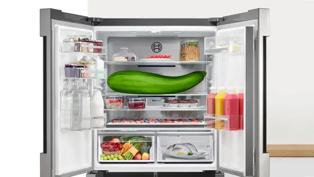 Refrigerador con las dos puertas abiertas. En su interior destacan una tarta de gran longitud y un calabacín gigante
