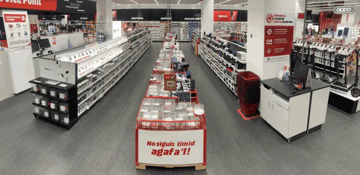 Interior de tienda con pasillos de estanterías llenas de productos. Muestra exhibidores centrales y letreros promocionales.