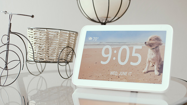 En una mesa, hay un despertador digital que marca las 9:05, una bicicleta decorativa de metal y una lámpara de techo colgante.