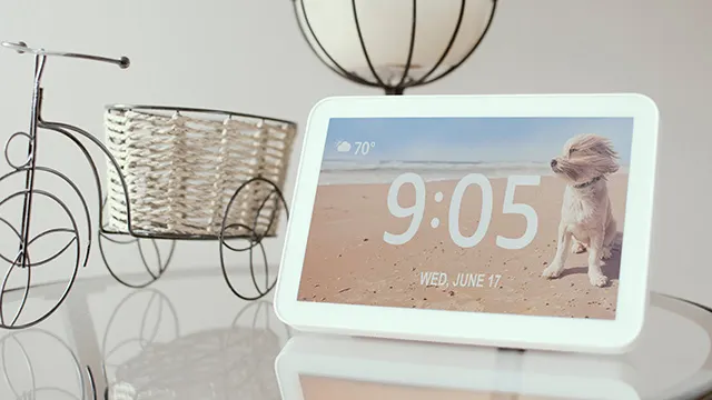 En una mesa, hay un despertador digital que marca las 9:05, una bicicleta decorativa de metal y una lámpara de techo colgante.