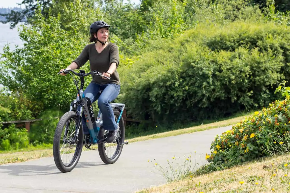 Mujer andando en bicicleta eléctrica por un camino al aire libre.