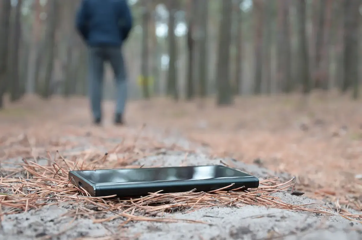 Hombre perdiendo su movil en el suelo del bosque