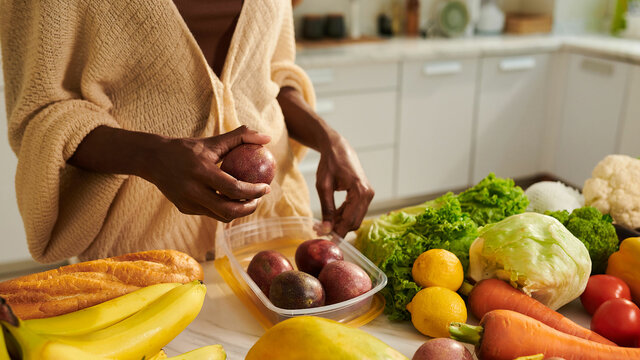 Mujer cogiendo frutas y verdura de la encimera