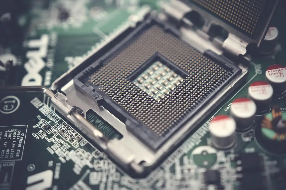 En primer plano, un zócalo de CPU detallado sobre una placa base verde con componentes electrónicos y la marca Dell visible.