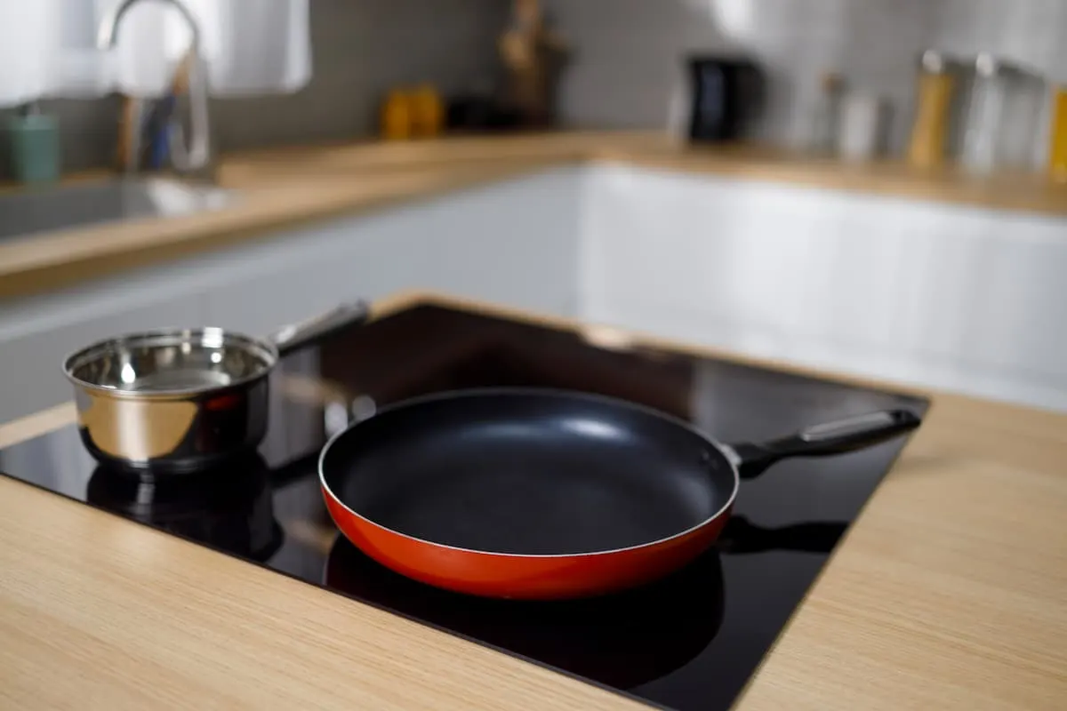 Sartén antiadherente roja sobre vitrocerámica en cocina moderna