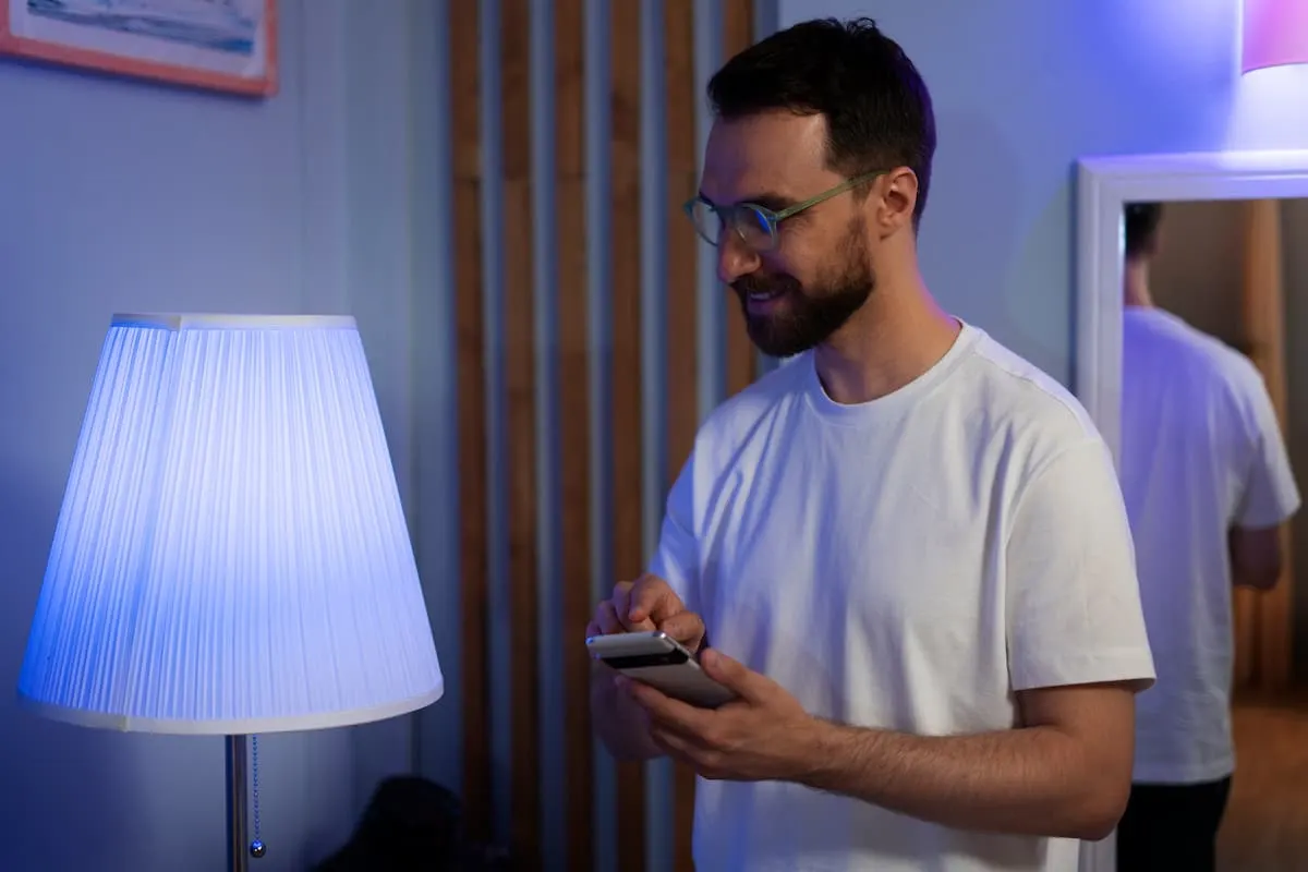 Hombre controlando una lámpara inteligente desde el móvil.