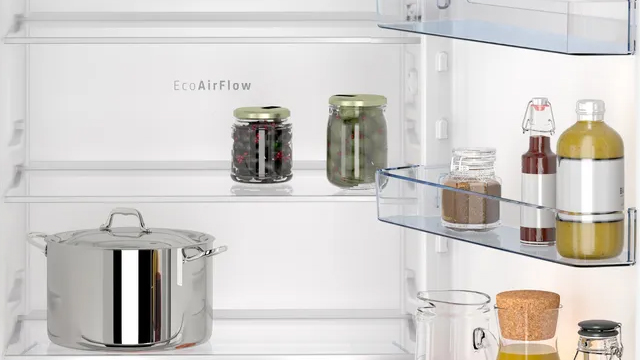 Detalle del interior del refrigerador. Sobre los estantes de cristal, tarros de conservas y una gran olla de acero inoxidable