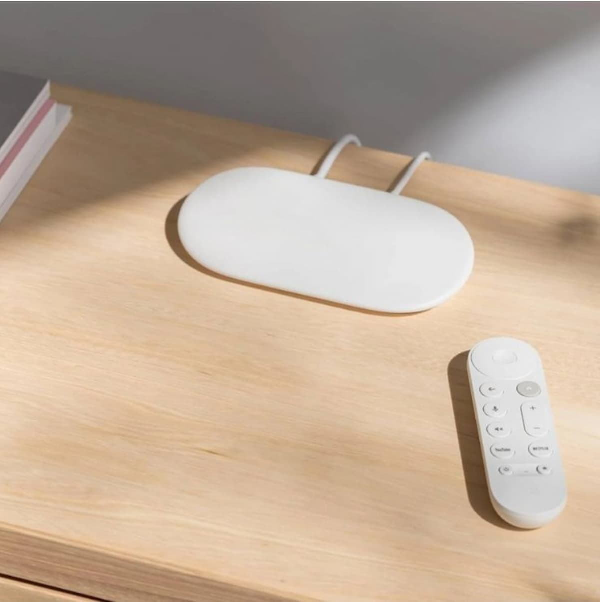 Chromecast blanco con mando sobre una mesa de madera.