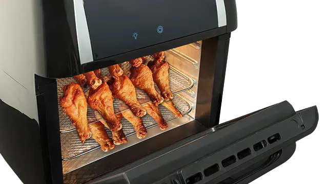 Freidora de aire negra con alitas de pollo cocinándose en una rejilla metálica. Puerta abierta. Interior iluminado.