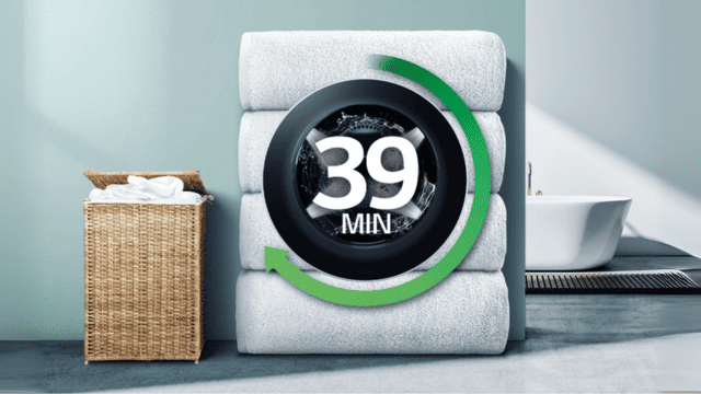 Lavadora LG con ciclo rápido de 39 minutos, sobre toallas apiladas junto a un cesto de ropa.