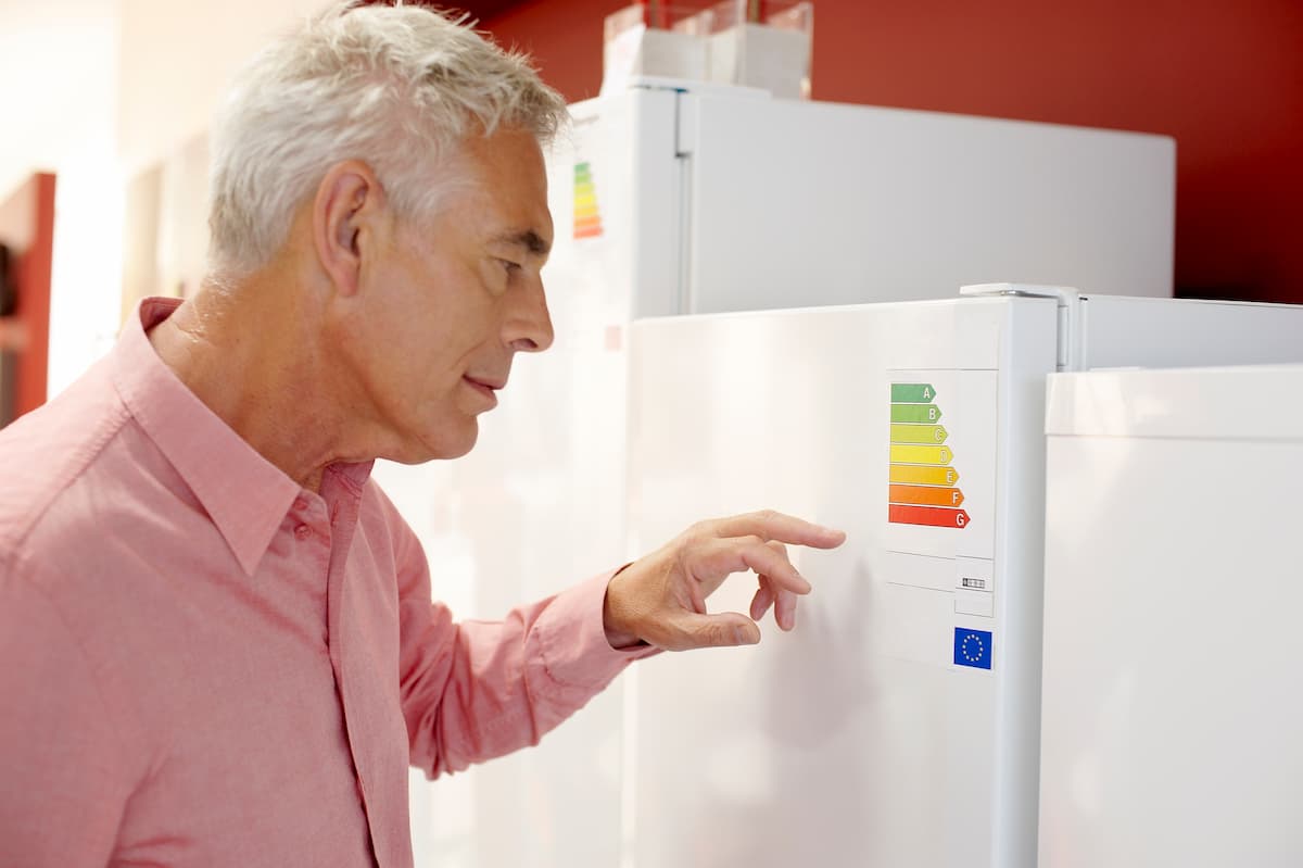 Hombre señalando etiqueta de eficiencia energética en refrigerador