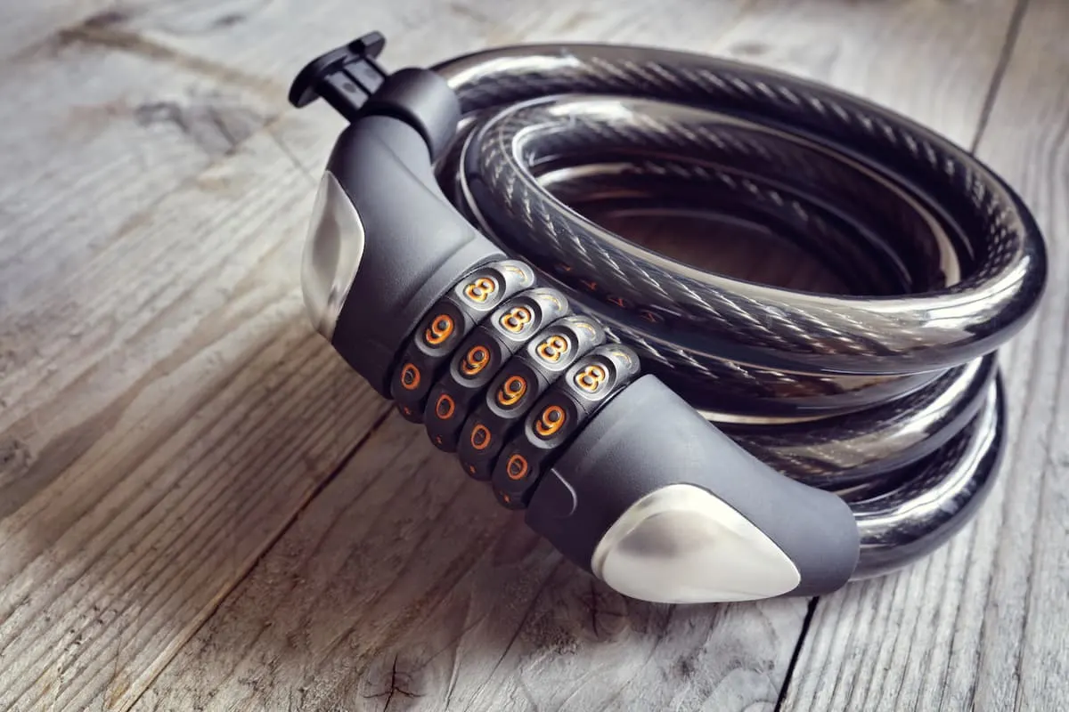 Candado de cable con combinación numérica enrollado sobre una superficie de madera.