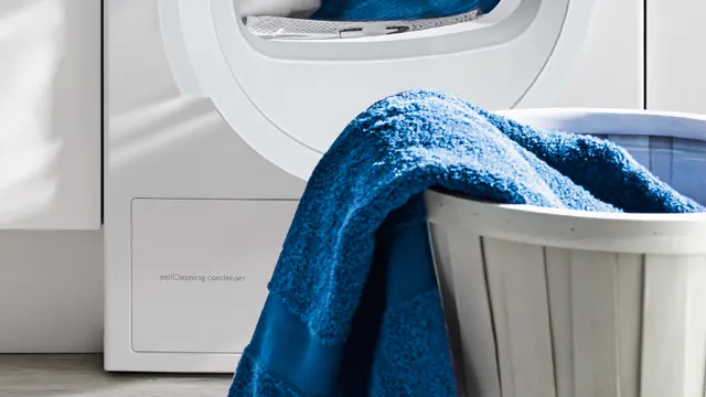 Detalle de una cesta de colada con toallas azules húmedas ante una secadora con sensor de humedad