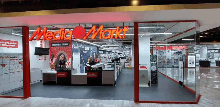 Entrada a tienda Media Markt con letrero naranja. Se ven cajas registradoras y pasillos con productos en venta.
