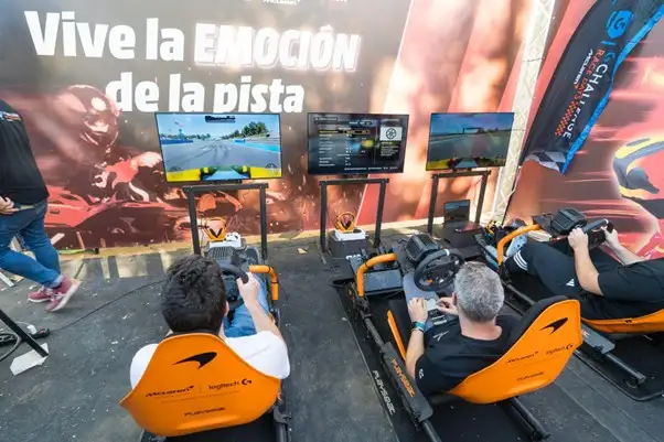 Personas jugando en simuladores de carreras en el stand de Kart Royale Granada.