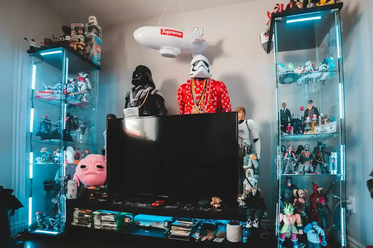 Estanterías de cristal iluminadas flanquean un televisor. Figuras de acción de Star Wars y otros objetos decoran la habitación.