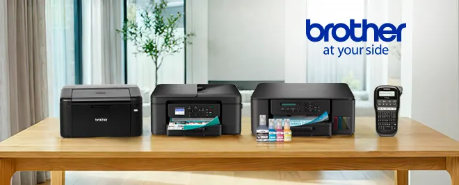 Impresoras y etiquetadora Brother sobre mesa de madera en salón moderno, con logo Brother “at your side” al fondo