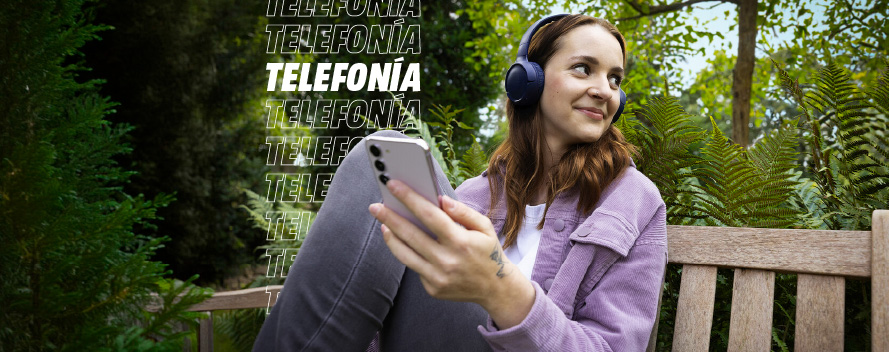 Mujer con auriculares azules sentada en banco de madera, sostiene móvil gris. Árboles y texto "Telefonía" de fondo.
