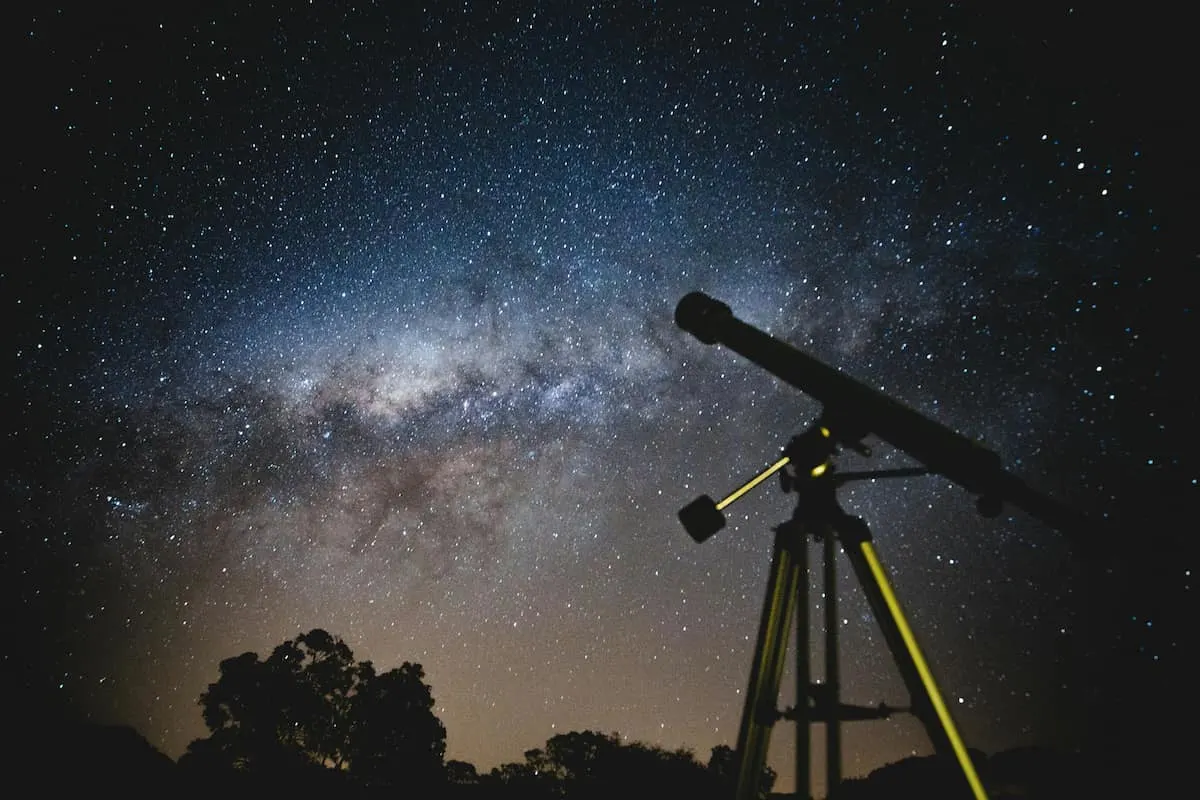 Telescopio apuntando al cielo estrellado de noche.