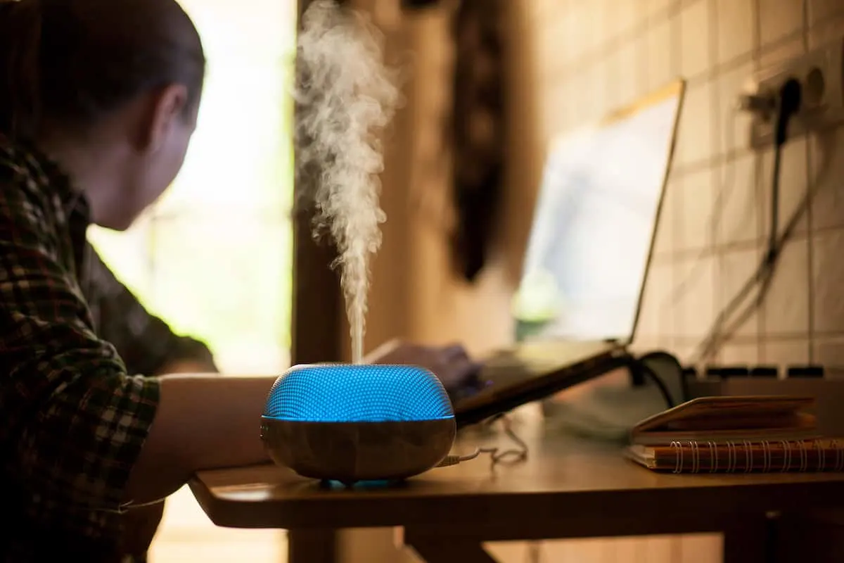 Humidificador emitiendo vapor junto a una persona trabajando.