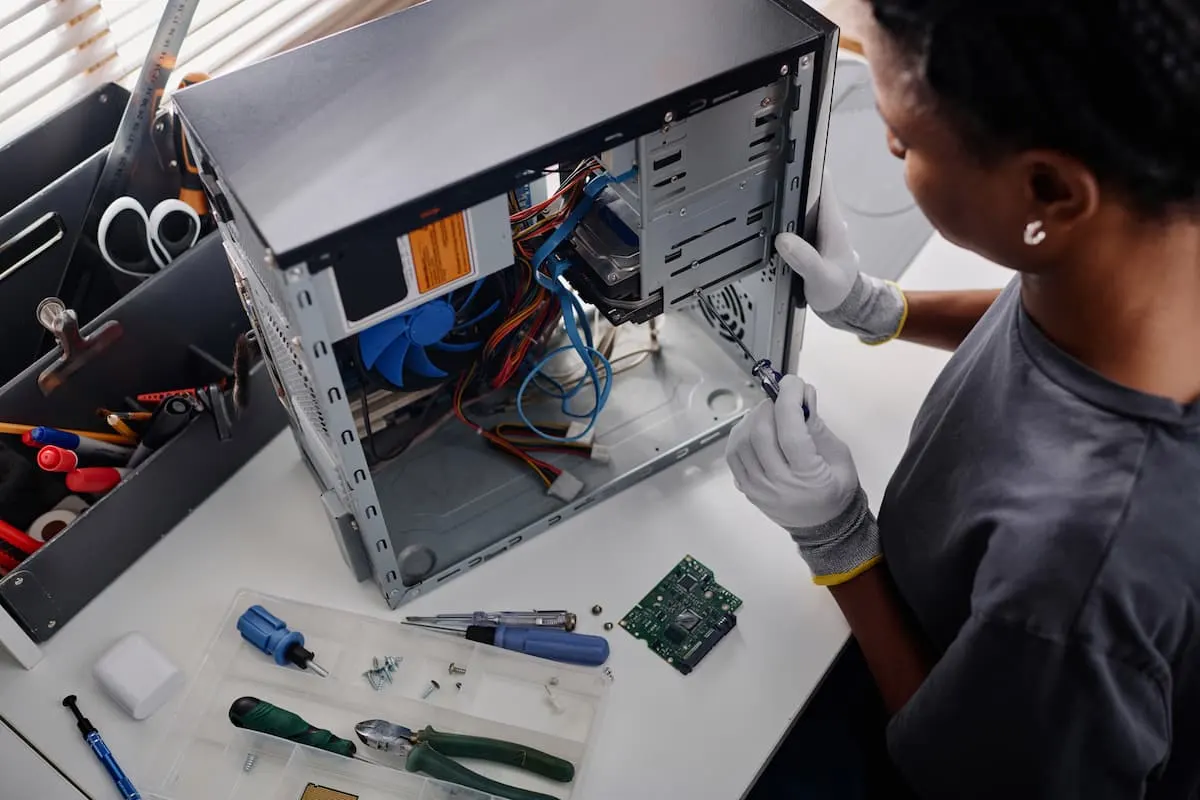 Técnica con guantes ensamblando el interior de una torre de PC en un escritorio con herramientas.