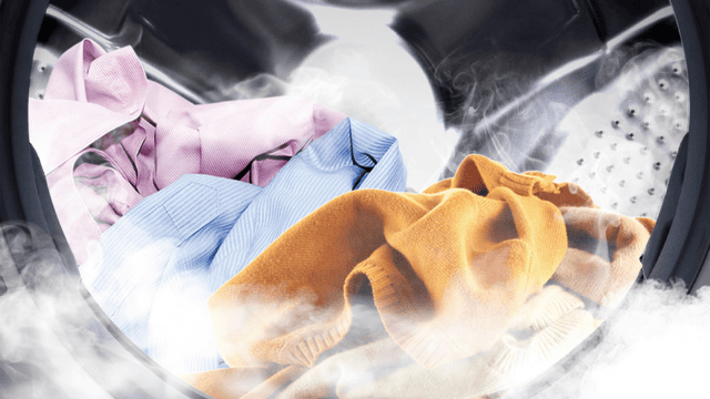 Ropa de colores dentro del tambor de la lavadora con vapor visible.