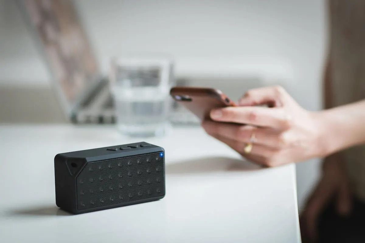 Altavoz Bluetooth negro junto a un móvil en una mesa