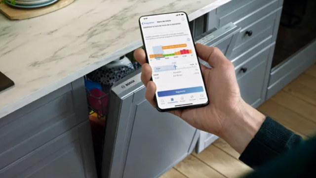 cocina con lavavajillas Bosch. Mano que sostiene smarthphone con la App Home connect abierta