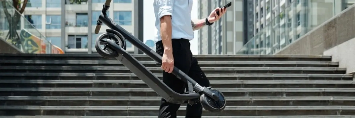 Hombre paseando con un patinete eléctrico plegado