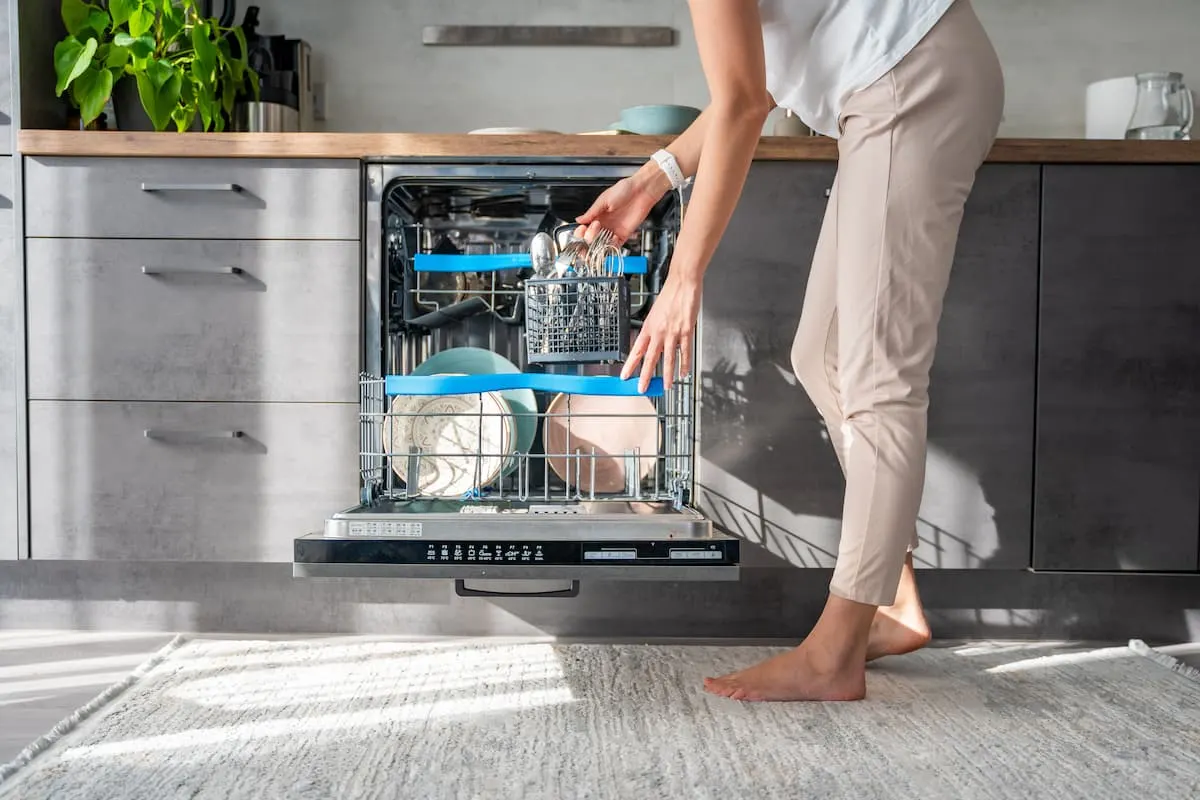 Persona colocando platos en lavavajillas integrado en cocina moderna