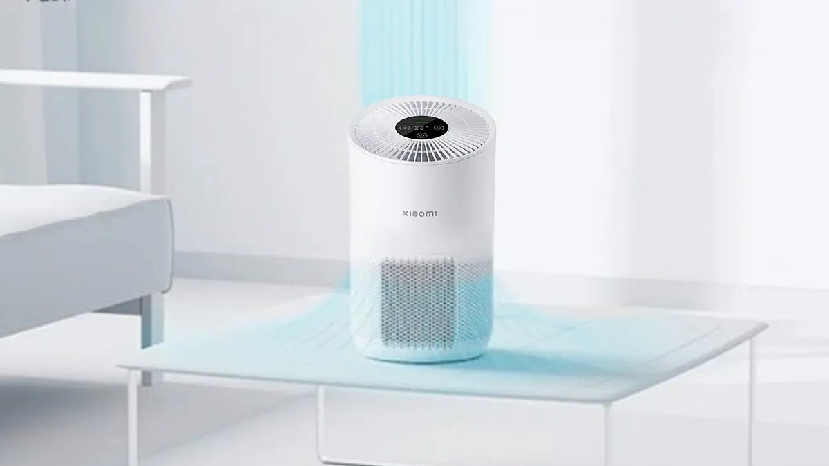 Xiaomi Smart Air Purifier 4 Compact hava temizleme cihazı bir odada, masanın üzerinde çalışıp havayı temizliyor ve filtreliyor