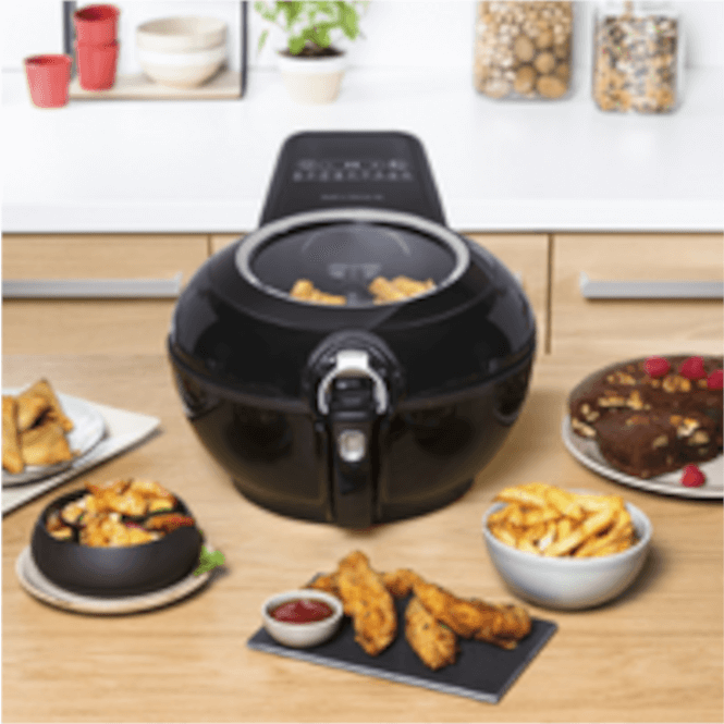 Siyah fritöz, patates kızartması, kek ve soslar ahşap tezgahta. Arkada mutfak dolapları ve aksesuarlar görülüyor.