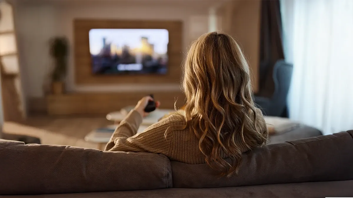 Evin salonunda OLED TV ile film izleyen kadın.