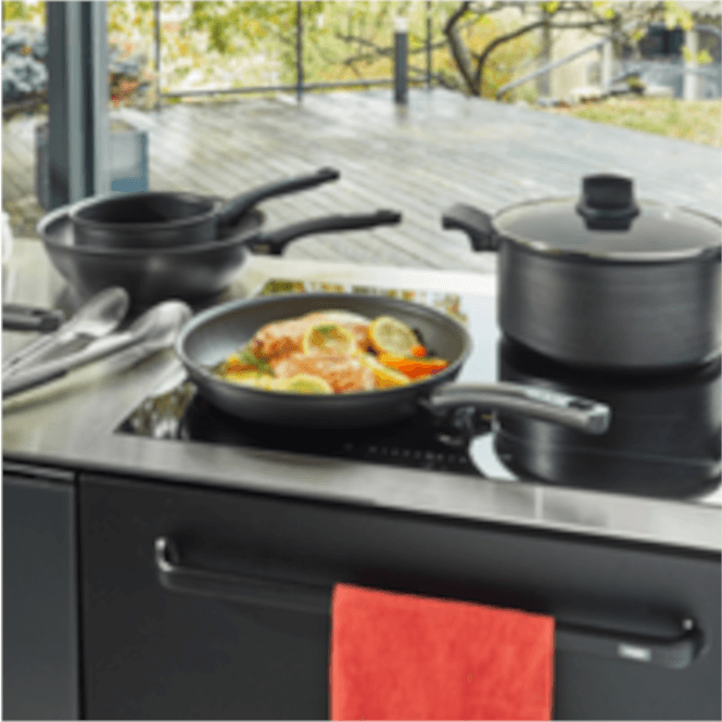 Siyah ocakta tencere, tava ve yemek pişiyor. Pencereden dışarıda ağaçlar ve zemin görülüyor. Kırmızı bir havlu asılı.