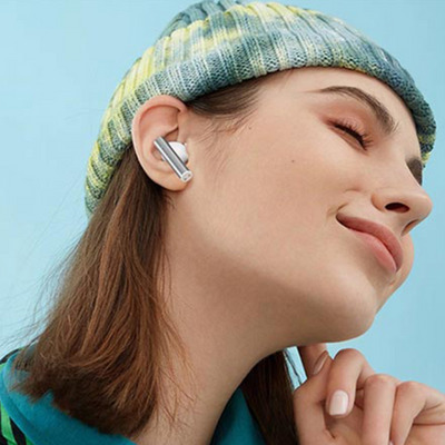 Açık mavi arka planda, kulaklık takan, bere takmış bir kadın gülümsüyor.