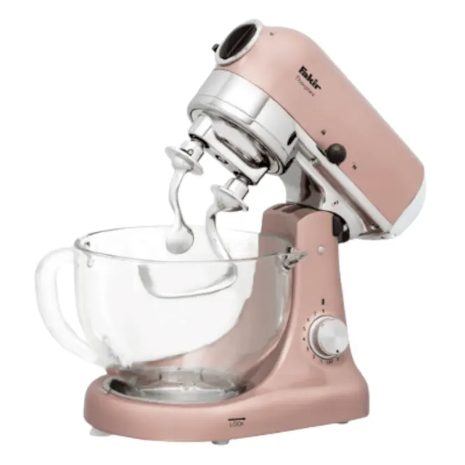 Pembe stand mikseri, cam kase ve çırpıcı başlıkları ile beyaz bir arka plan üzerinde duruyor.