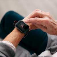 Yakın çekimde, kolunda siyah akıllı saat olan ve bir yastığa yaslanan bir el görülüyor.