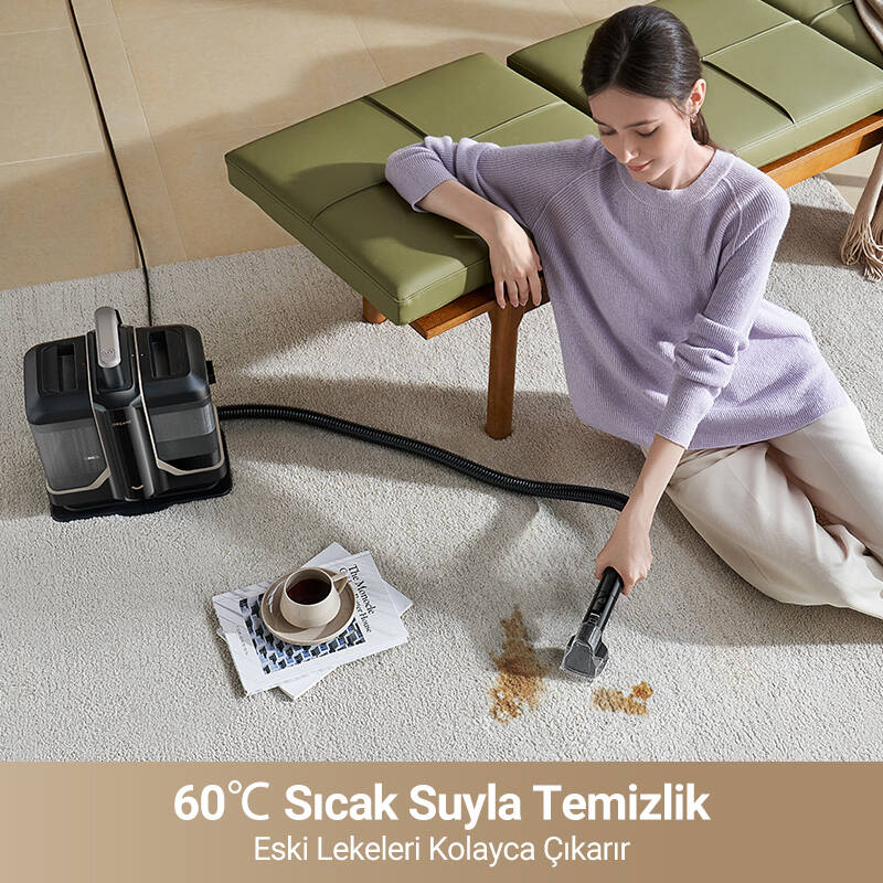 Halıda leke temizleyen kadın. Yanda temizleme cihazı, kitap ve kahve fincanı var.