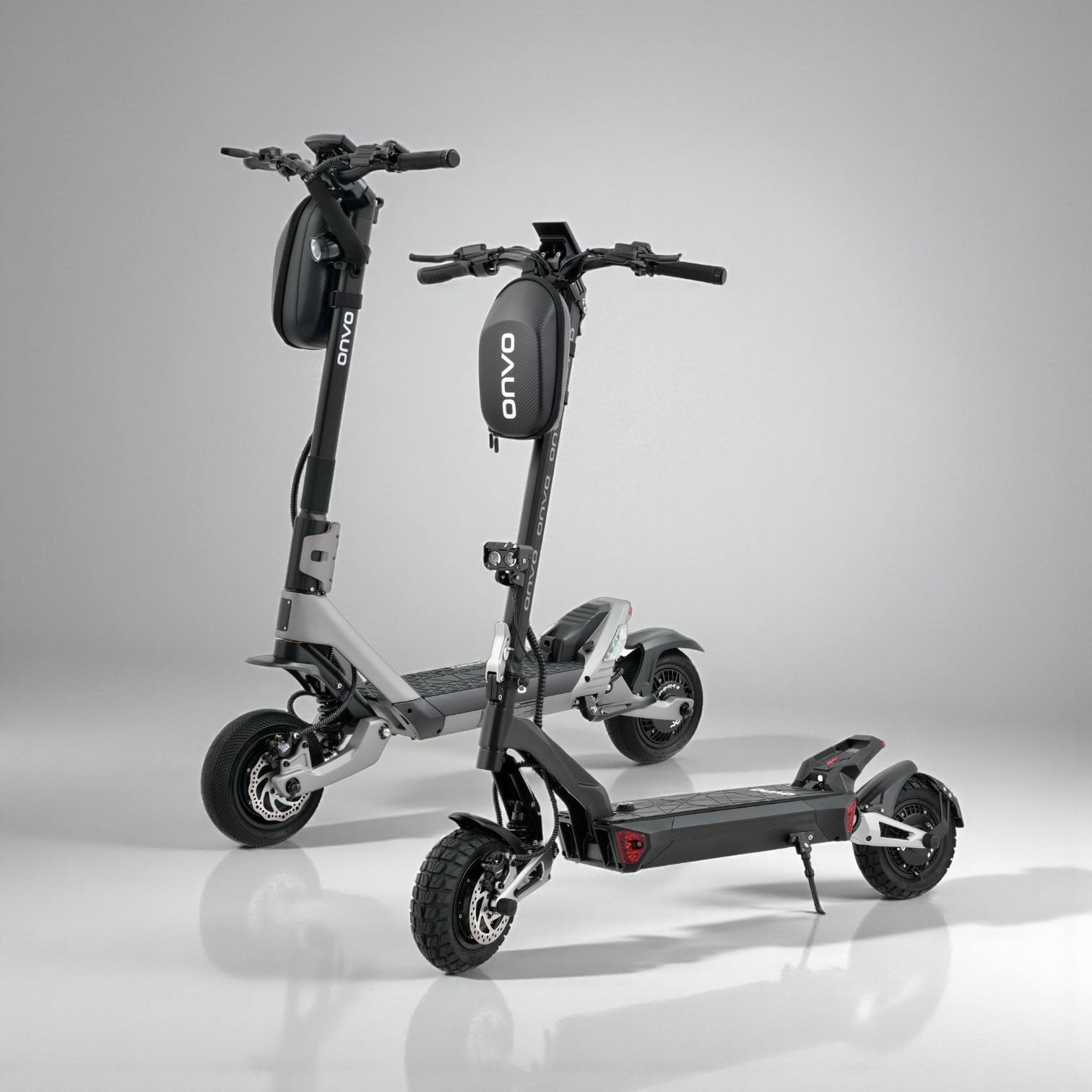 Gri bir elektrikli scooter, koyu renkli yatay kaplamalı bir duvarın önünde duruyor. Sağda bulanık bir figür görülebilir.