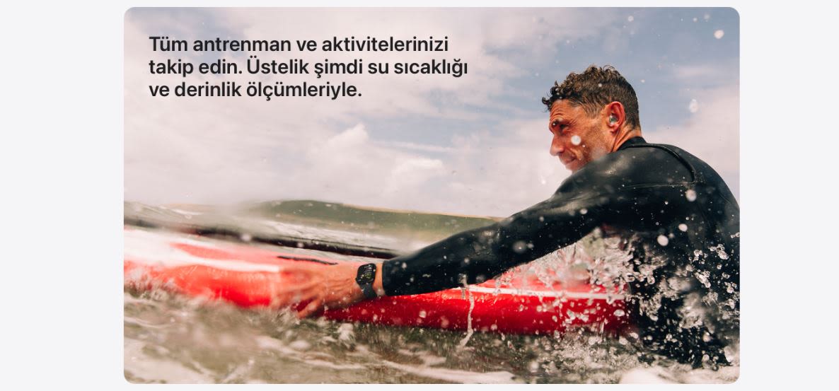 Denizde kırmızı sörf tahtası üzerinde siyah dalgıç giysisi giyen bir adam sörf yapıyor. Arkada dalgalar ve gökyüzü var.