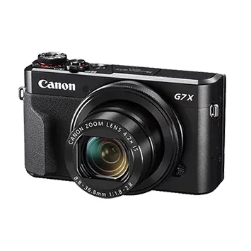 Siyah Canon G7X fotoğraf makinesi, mercek ve düğmeleri net gösteriyor. Beyaz arka plan üzerinde duruyor.