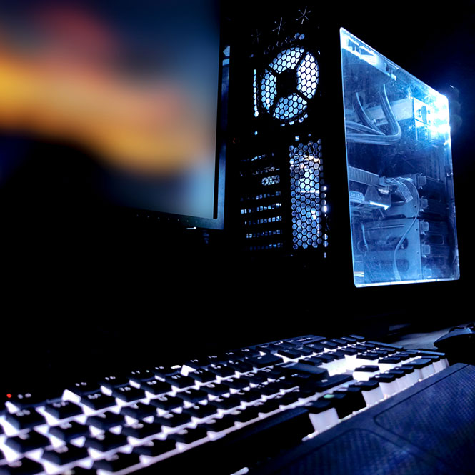 Siyah kasalı, mavi ışıklı bilgisayar, klavye ve ekran. Masa üstünde duruyor.