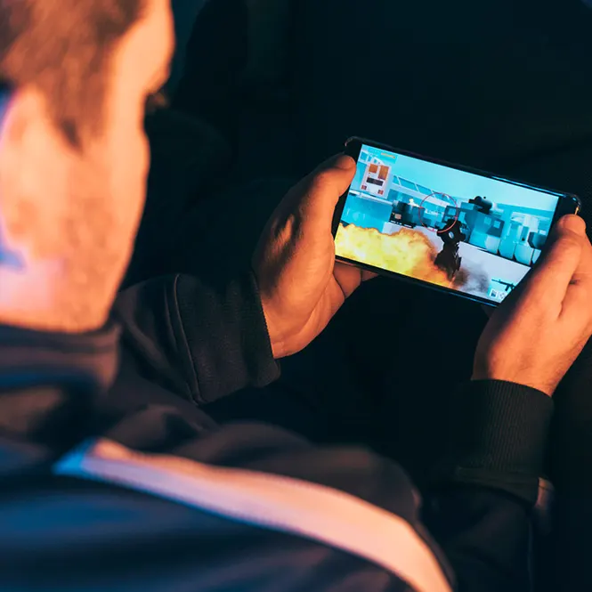 Cepheden bir adamın telefon oyunu oynadığı görülüyor. Adamın omzu ve başı bulanık, telefon ekranı net.
