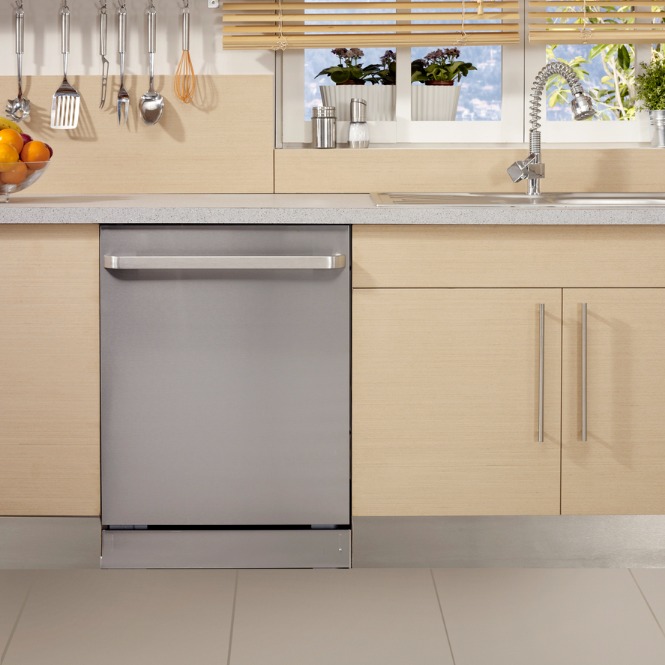 Mutfak tezgahında gri bulaşık makinesi, bej dolaplar, musluk ve pencere görülmektedir.