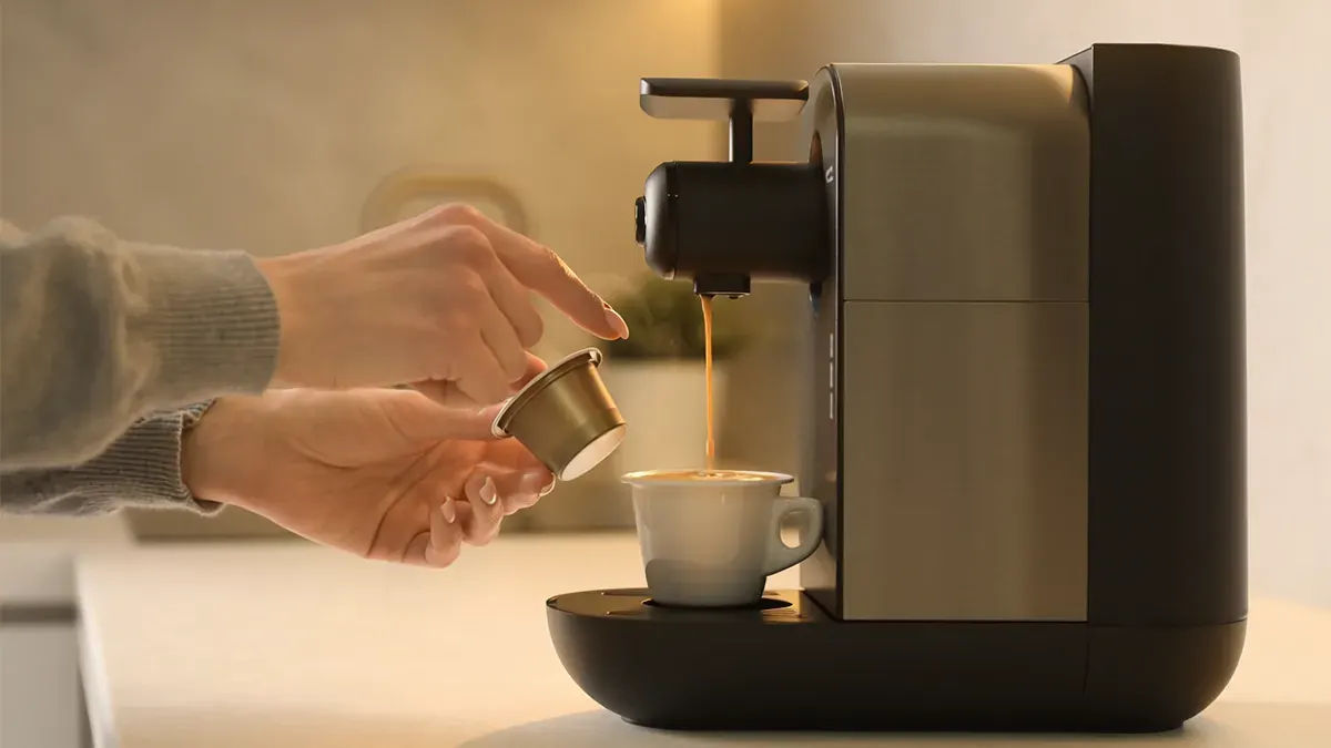 Tezgahta duran espresso makinesi ile bir kullanıcı fincana kahve dolduruyor.