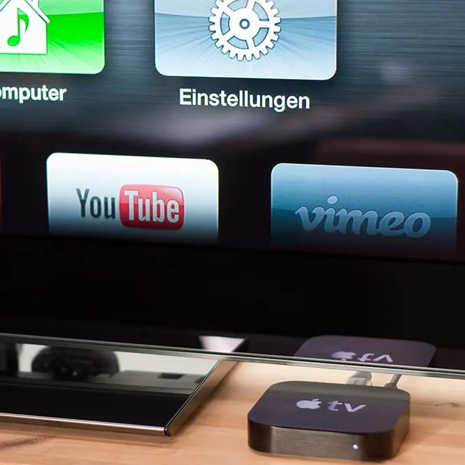 Apple TV arayüzü YouTube ve Vimeo uygulamalarıyla bir televizyon ekranında görülüyor.