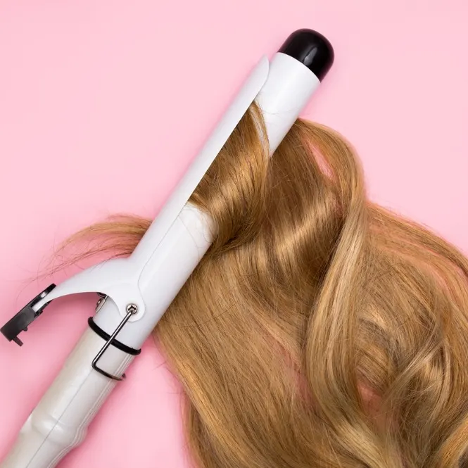 Pembe zemin üzerinde, sarı saç tutamının etrafına sarılmış beyaz bir saç maşası görülmektedir.